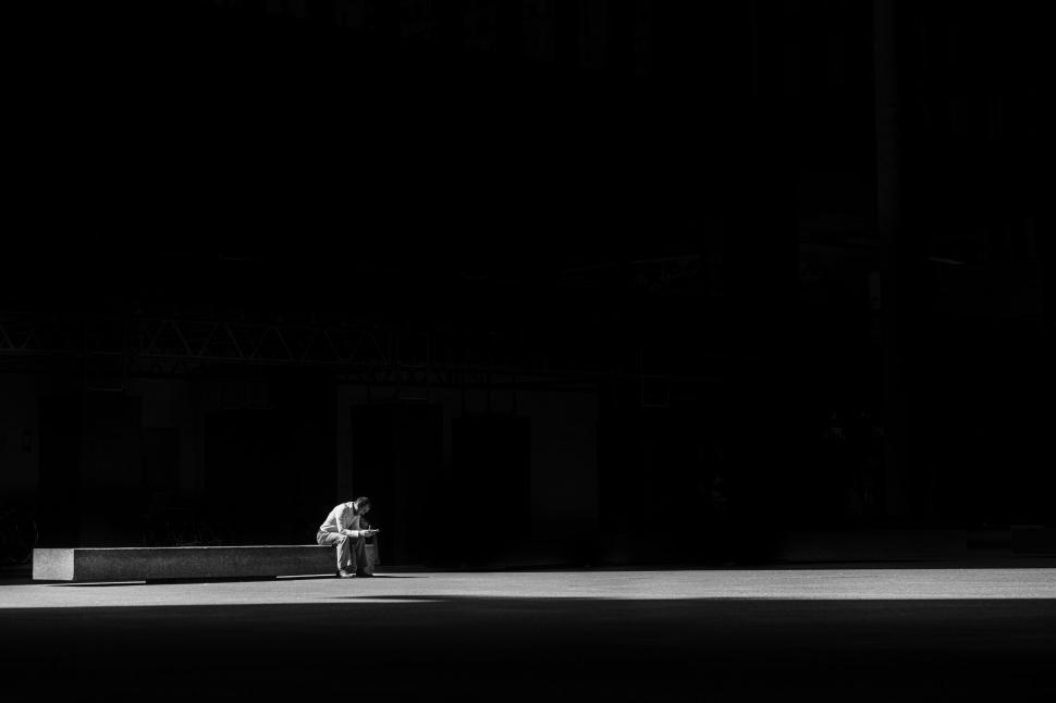 Free Image of Solitary figure sitting in a pool of sunlight 