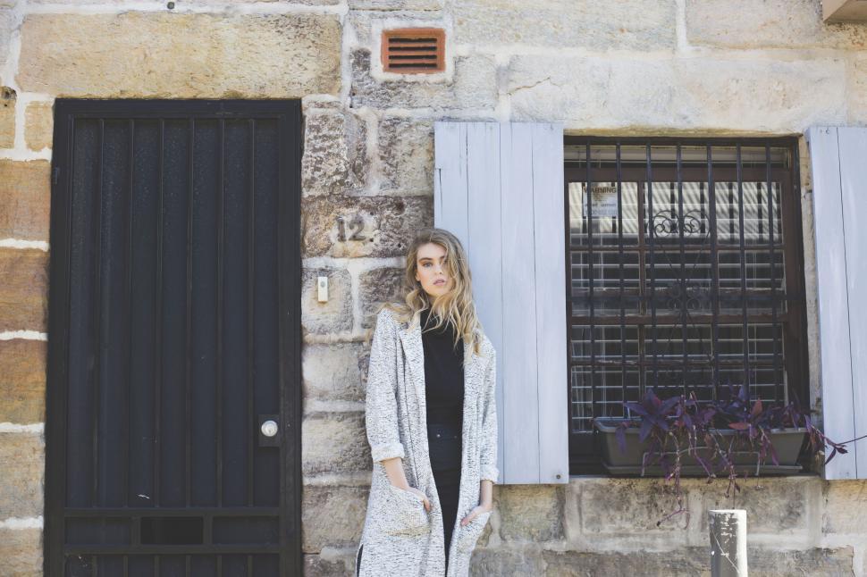 Free Image of Stylish woman posing by a stone house 