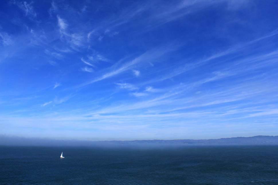 Free Image of Sailboat in the vast blue ocean under sky 