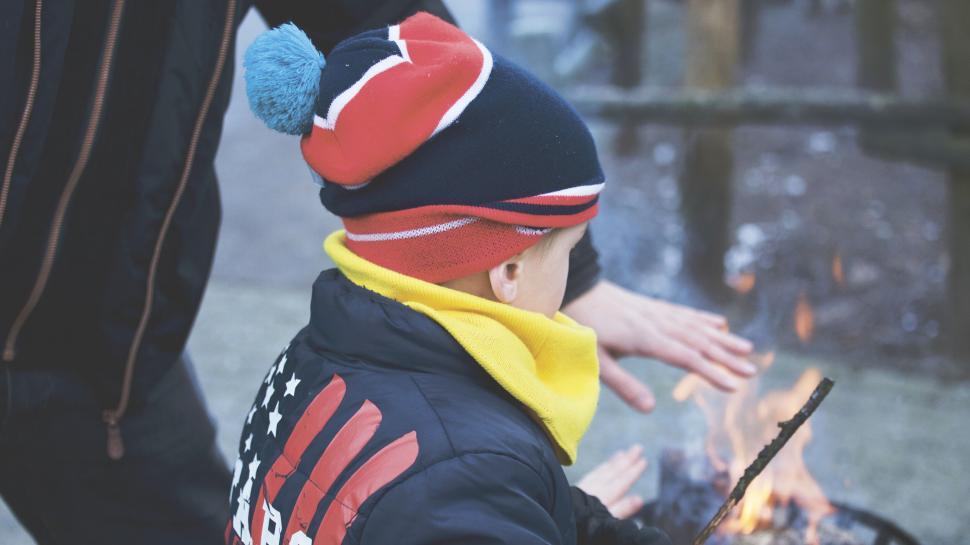 Free Image of Child warming hands over a cozy outdoor fire 