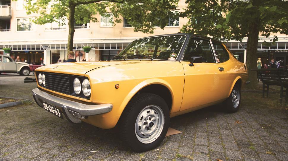 Free Image of Vintage yellow car parked at outdoor event 