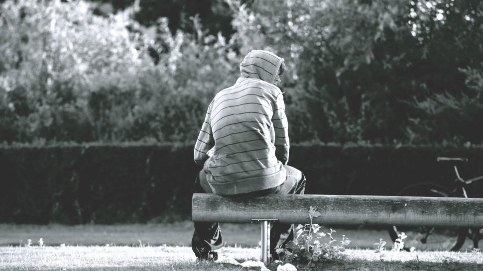 Free Image of Person sitting alone on a bench in grayscale 