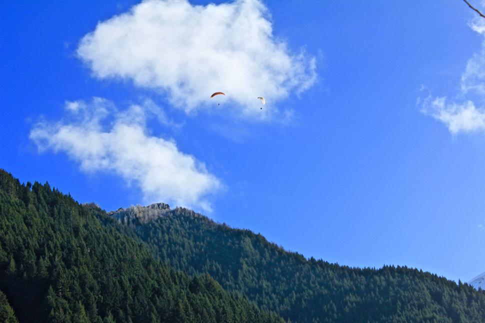Free Image of Paragliders soaring above mountainous landscape 