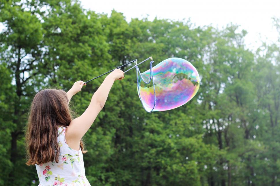Free Image of Girl creating a large colorful soap bubble 
