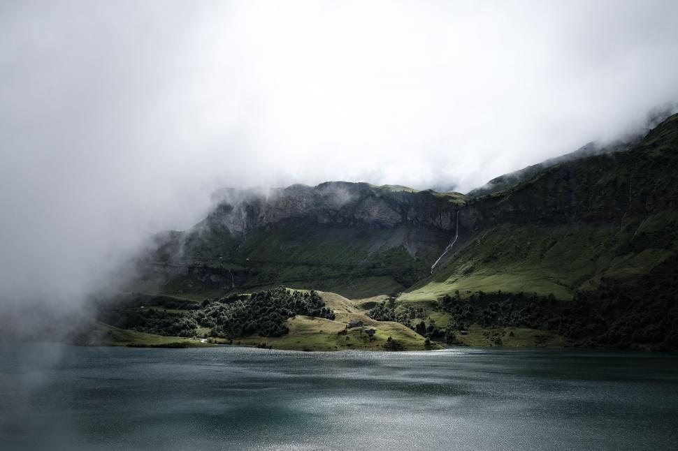 Free Image of Misty lake with green hills and low clouds 