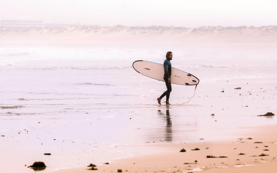 Free Image of Surfer walking on beach with surfboard 