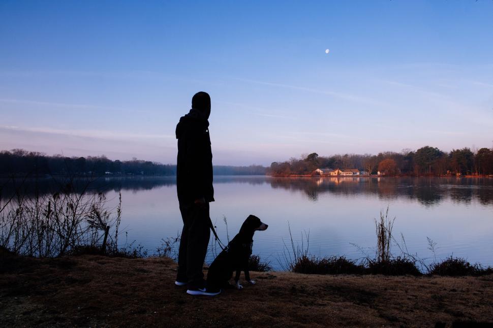 Free Image of Man and dog enjoy sunset by the lake 