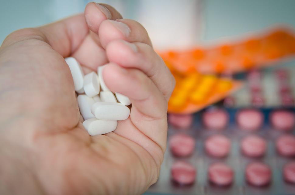 Free Image of Handful of white pills over blurred pills 