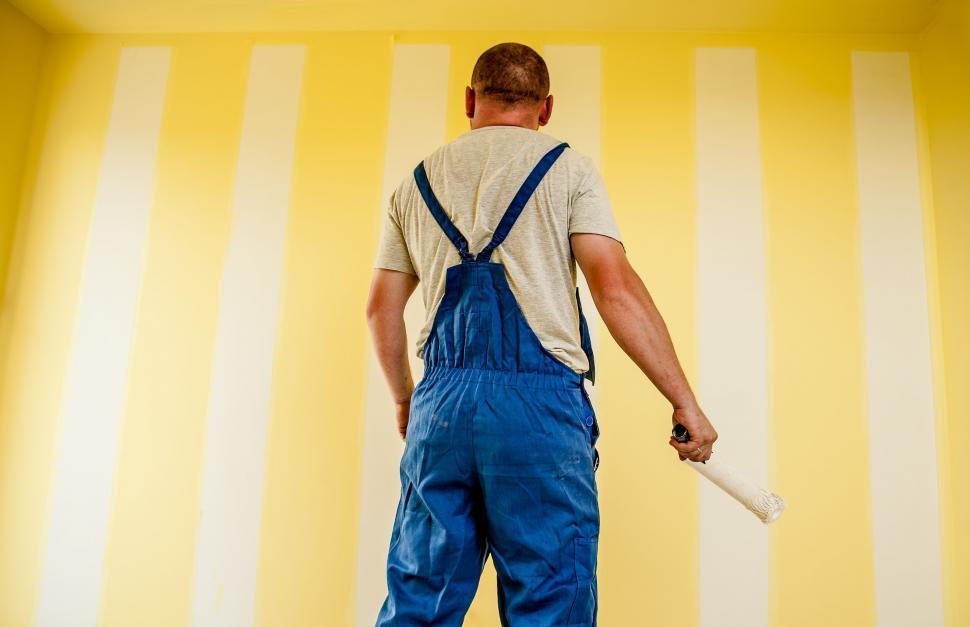 Free Image of Painter in overalls painting a yellow wall 