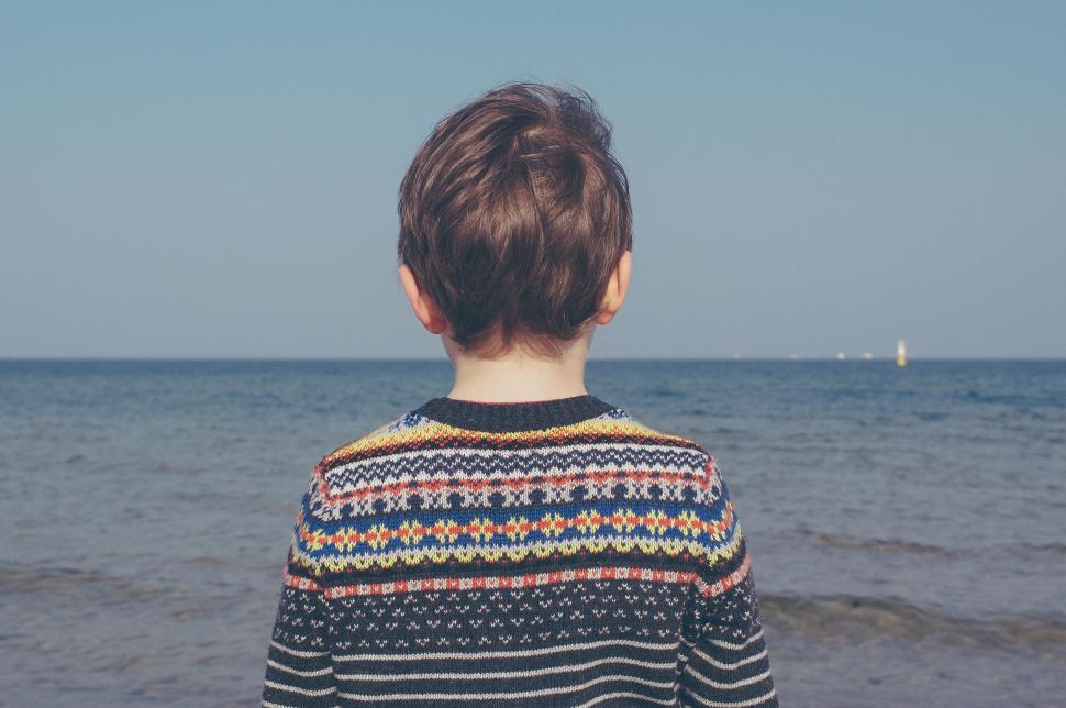 Free Image of Child looking out at calm sea horizon 
