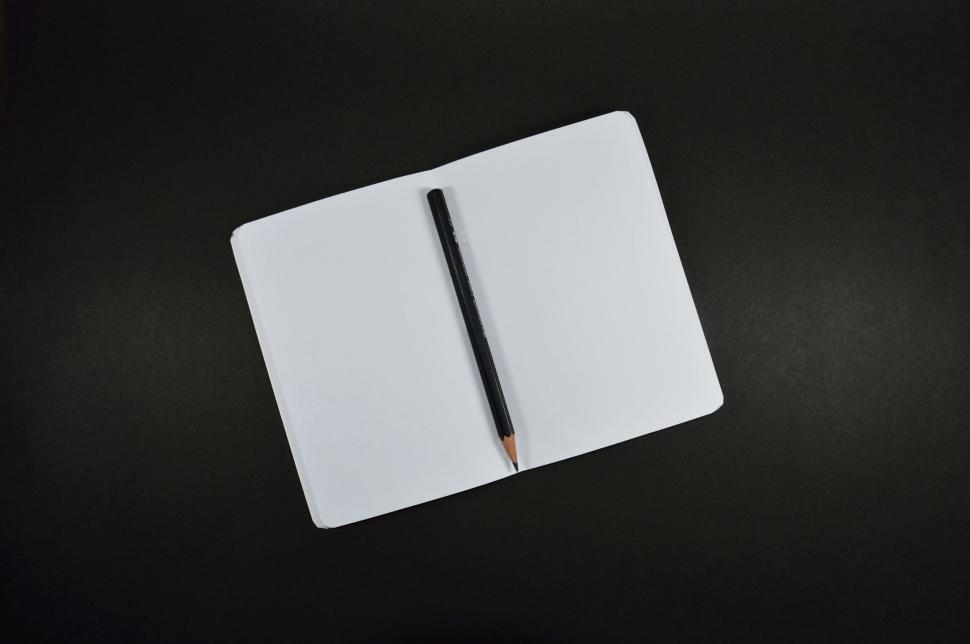Free Image of Open notebook with black pencil on black background 