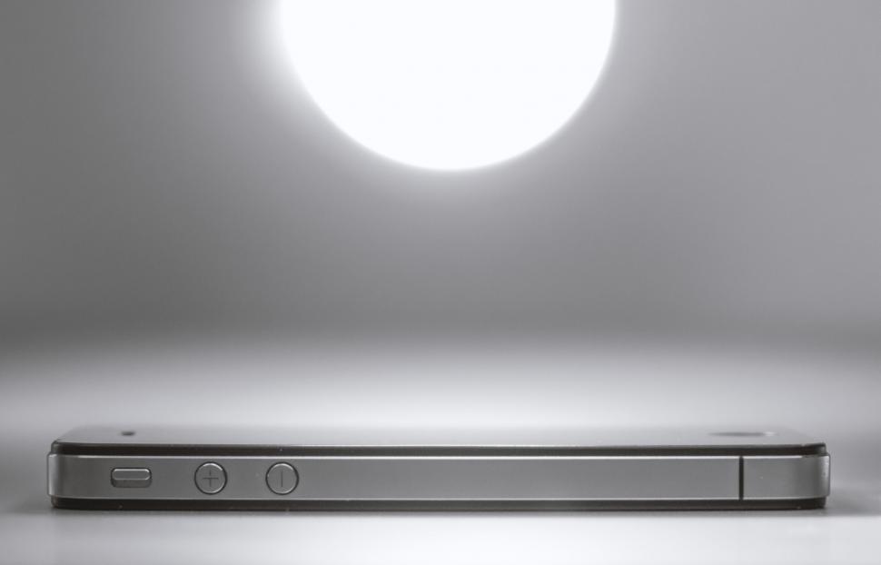 Free Image of Smartphone lying on a table with light above 