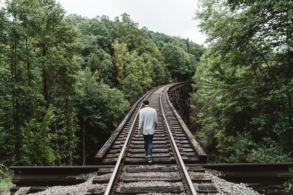 Free Image of Man walking on railroad tracks in woods 