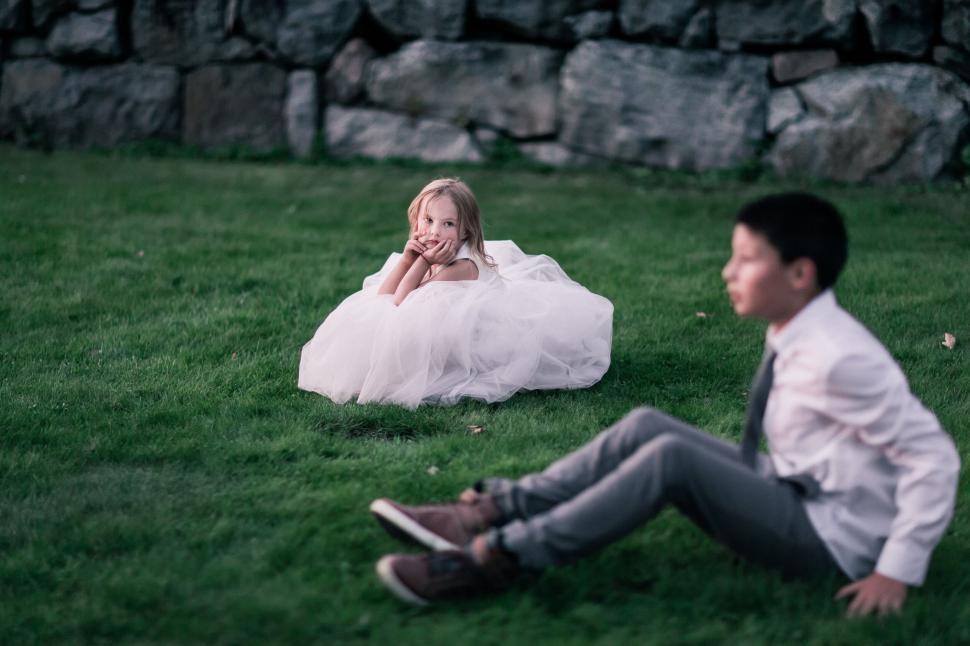 Free Image of Little girl in a white dress sitting on grass 
