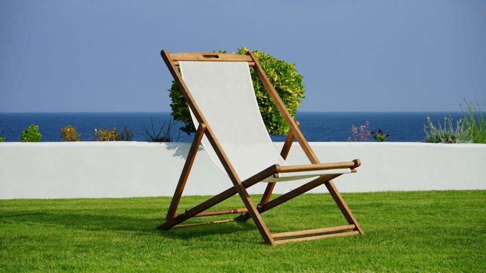 Free Image of Single deck chair facing the sea on a sunny day 