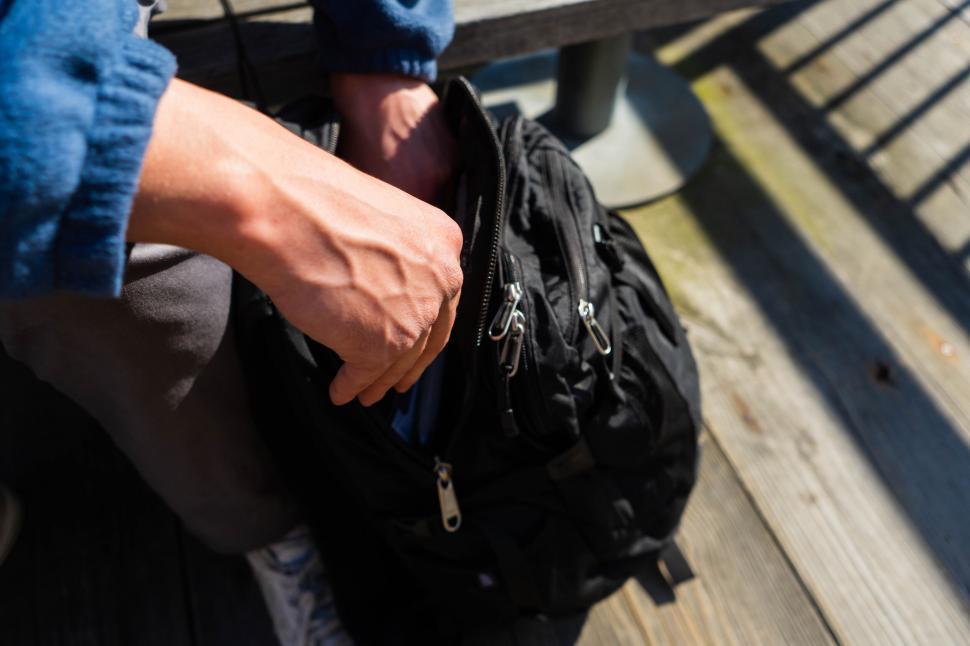 Free Image of Close-up of person zipping a black backpack 