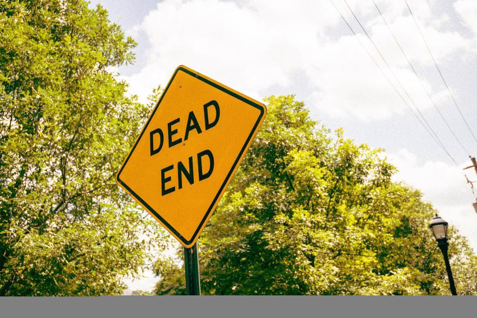 Free Image of Yellow dead end sign amidst lush greenery 