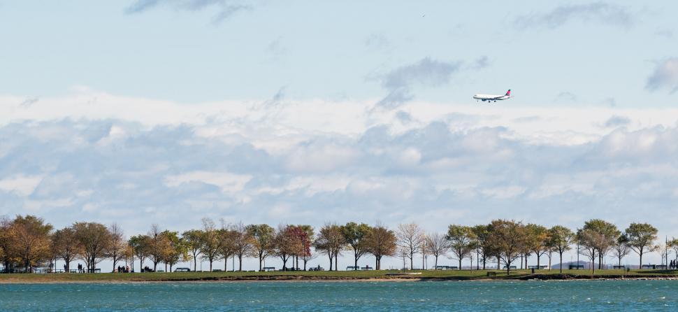 Free Image of Airplane flying over a scenic waterfront park 