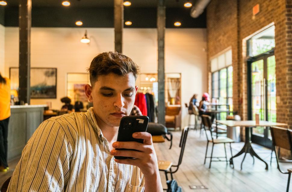 Free Image of Young man focused on smartphone in cafe 