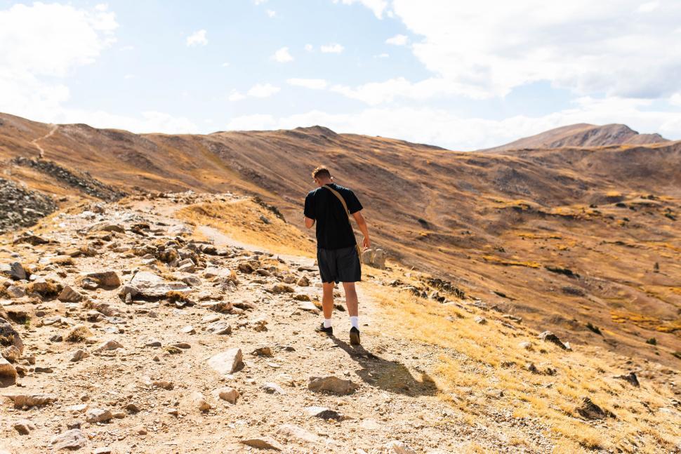 Free Image of Man hiking on rocky mountain trail 