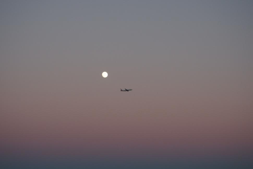 Free Image of Airplane silhouette against evening sky and moon 
