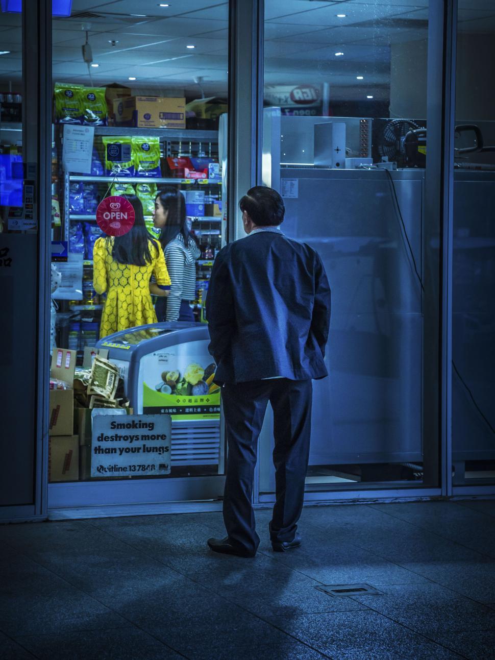 Free Image of Man looking at store window at night 