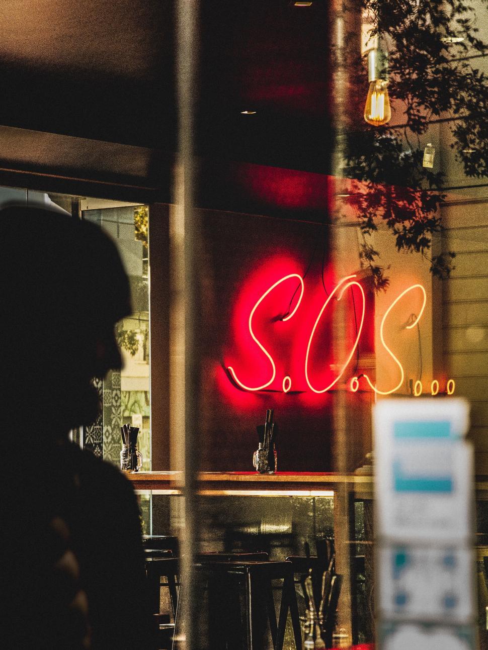 Free Image of Neon Sign SOS in a Window Reflection 
