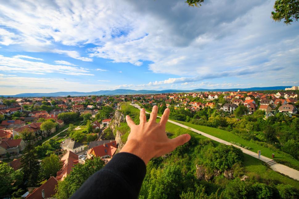 Free Image of Hand reaching out to scenic town view 