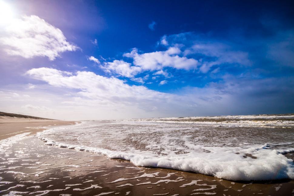 Free Image of Ocean shore with incoming tide and blue sky 