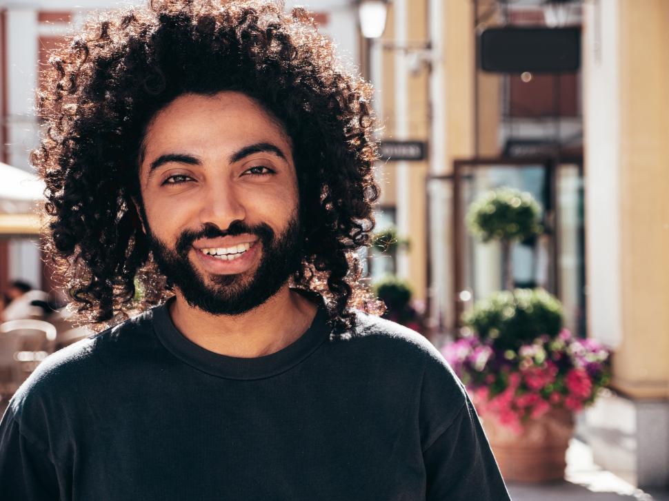 Free Image of A man with curly hair and beard smiling 