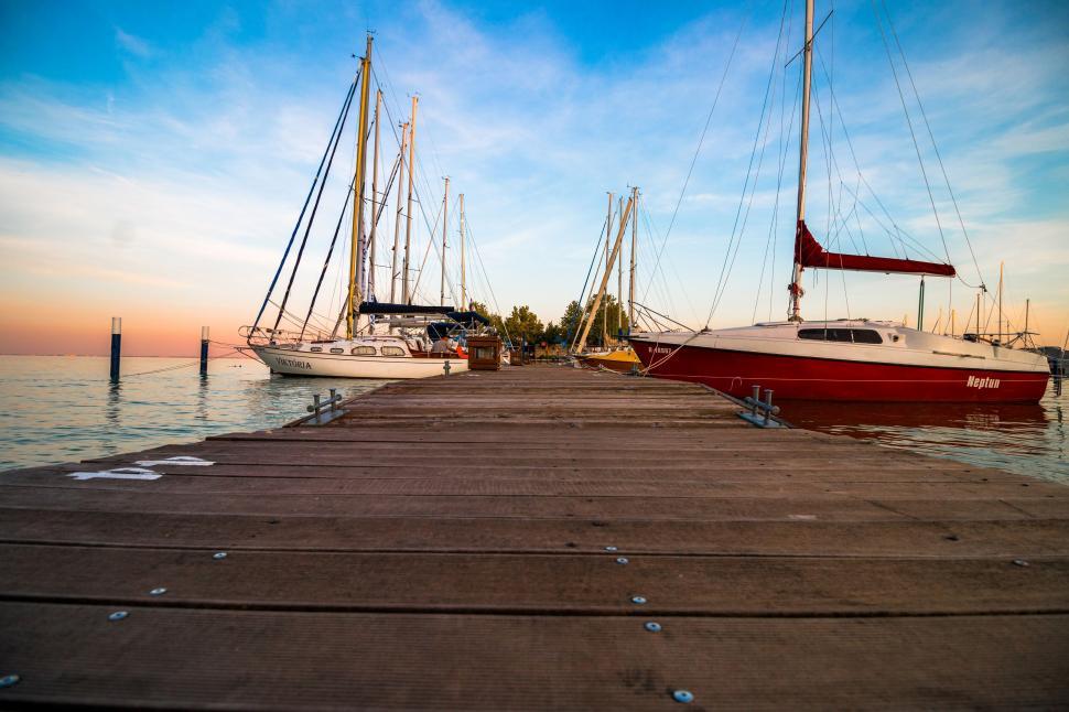 Free Image of Serene dock with moored sailboats at sunset 