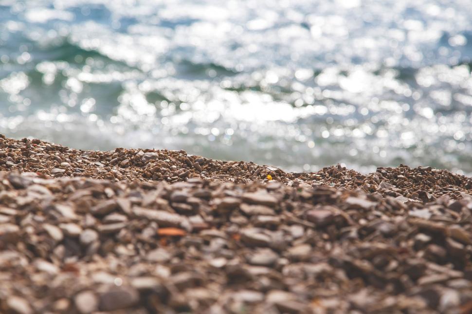 Free Image of Pebbled beach with shimmering sea in background 