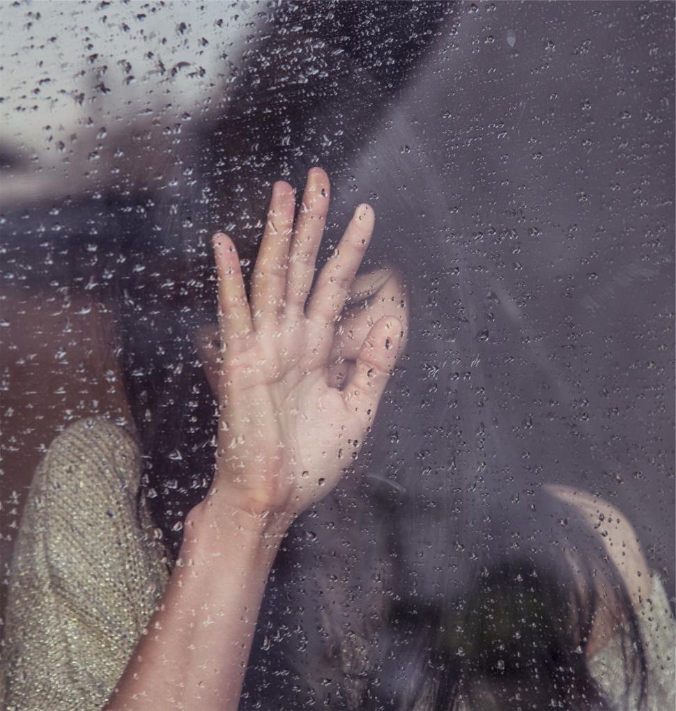 Free Image of Rain-soaked hand pressed against window 