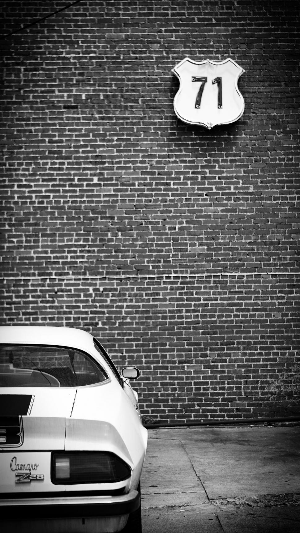 Free Image of Vintage Camaro by a brick wall with a 71 sign 