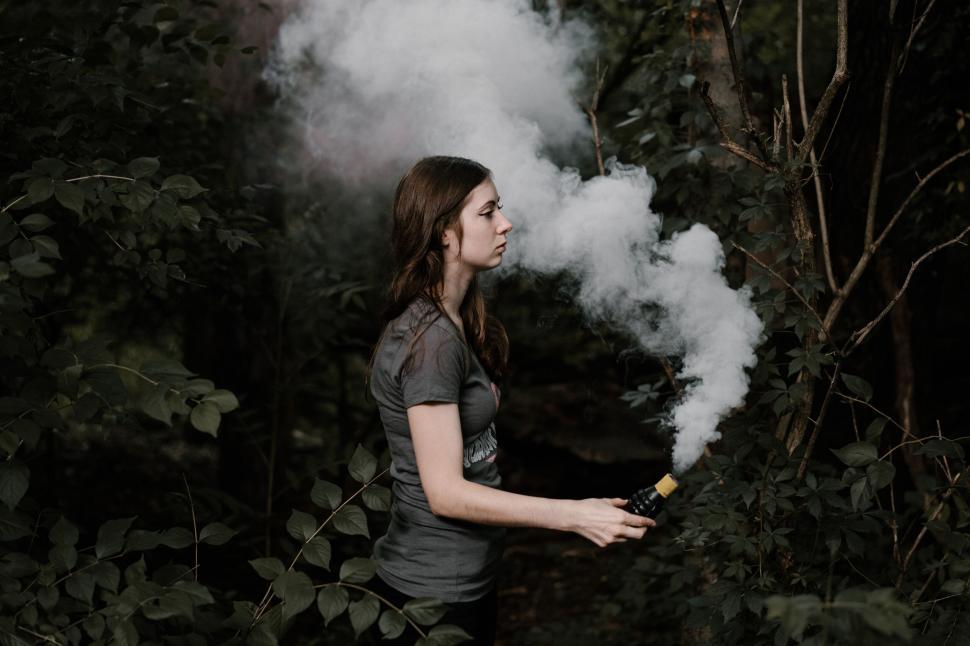 Free Image of Woman exhaling vapor in wooded area 