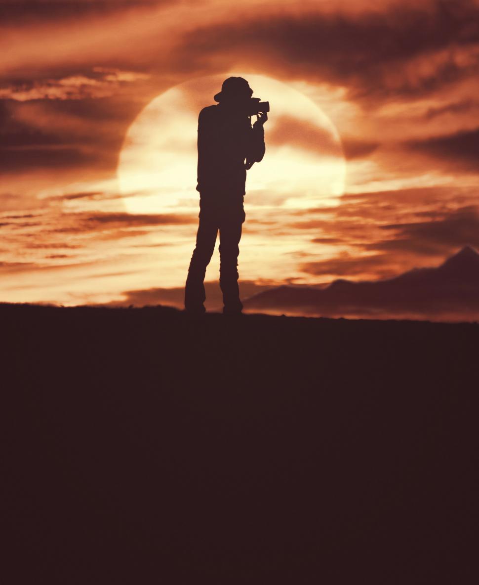 Free Image of Photographer silhouetted against a sunset 