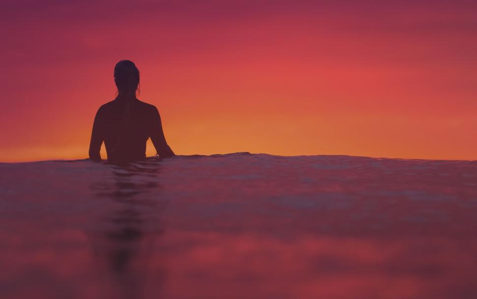 Free Image of Silhouette of a swimmer in red ocean waters 