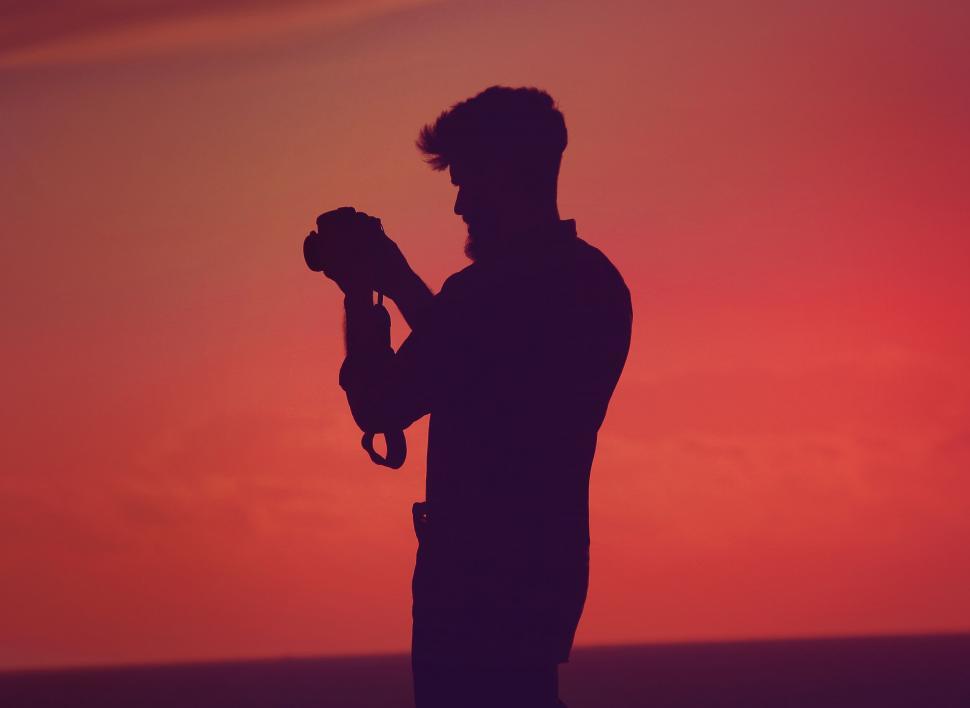 Free Image of Photographer s silhouette against sunset sky 