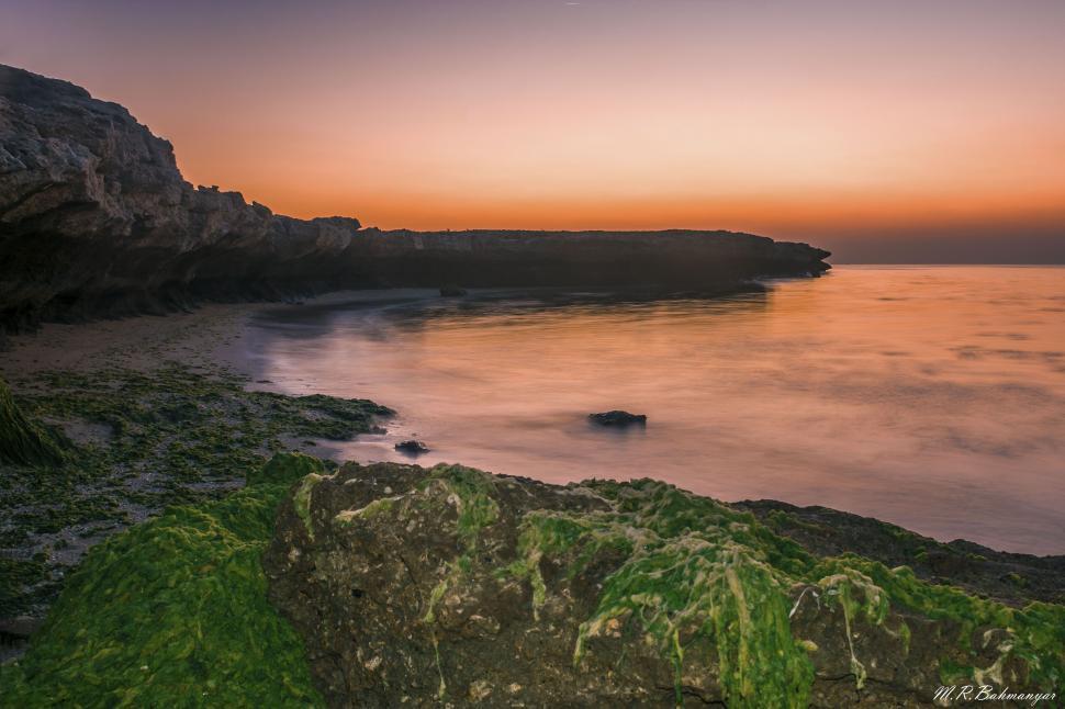 Free Image of Sunset colors reflecting off rocky coastline 