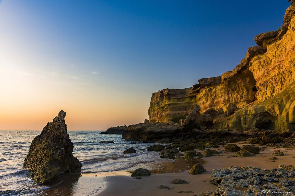Free Image of Golden hour at a rugged cliff beach shore 