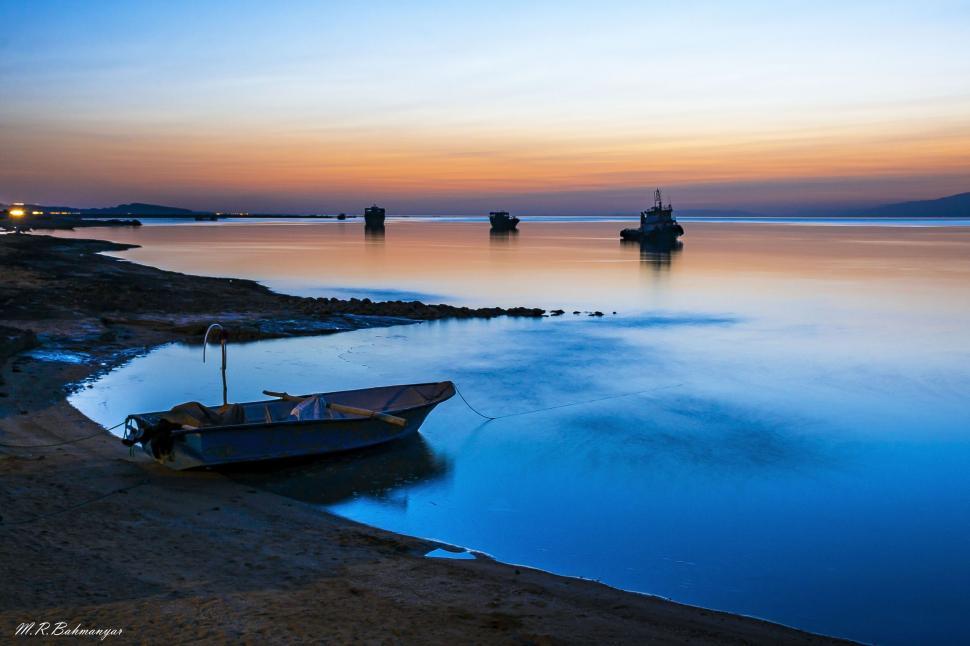 Free Image of Sunset hues over calm bay with boats 