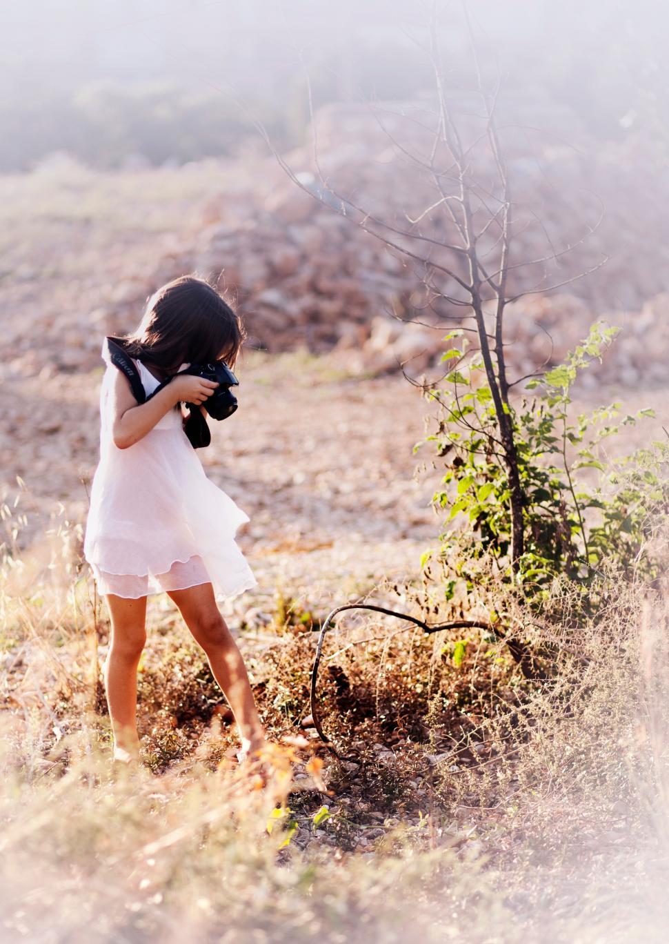 Free Image of Young girl photographing in a field at sunset 