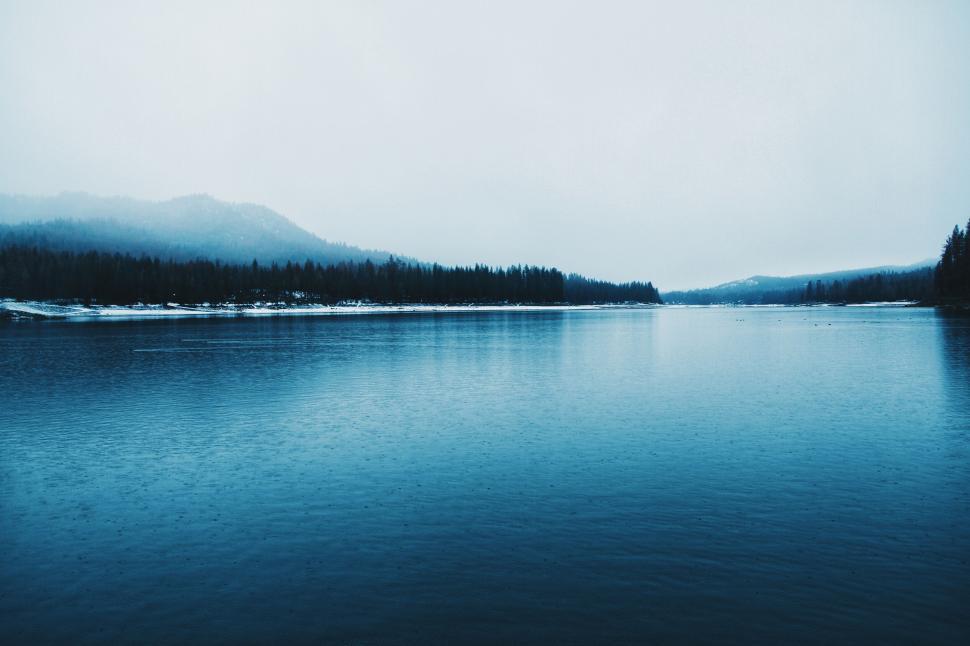 Free Image of Misty lake view with snowy forest backdrop 