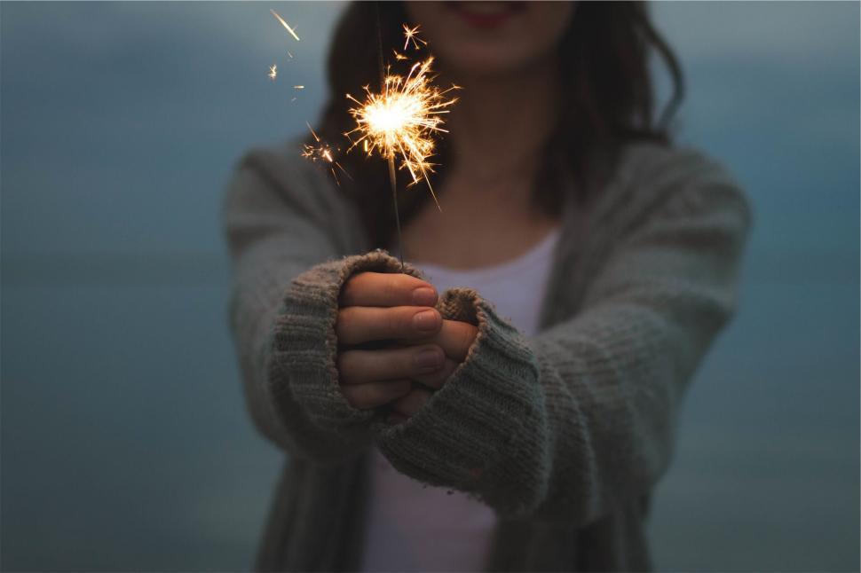 Free Image of Woman holding a lit sparkler in darkness 