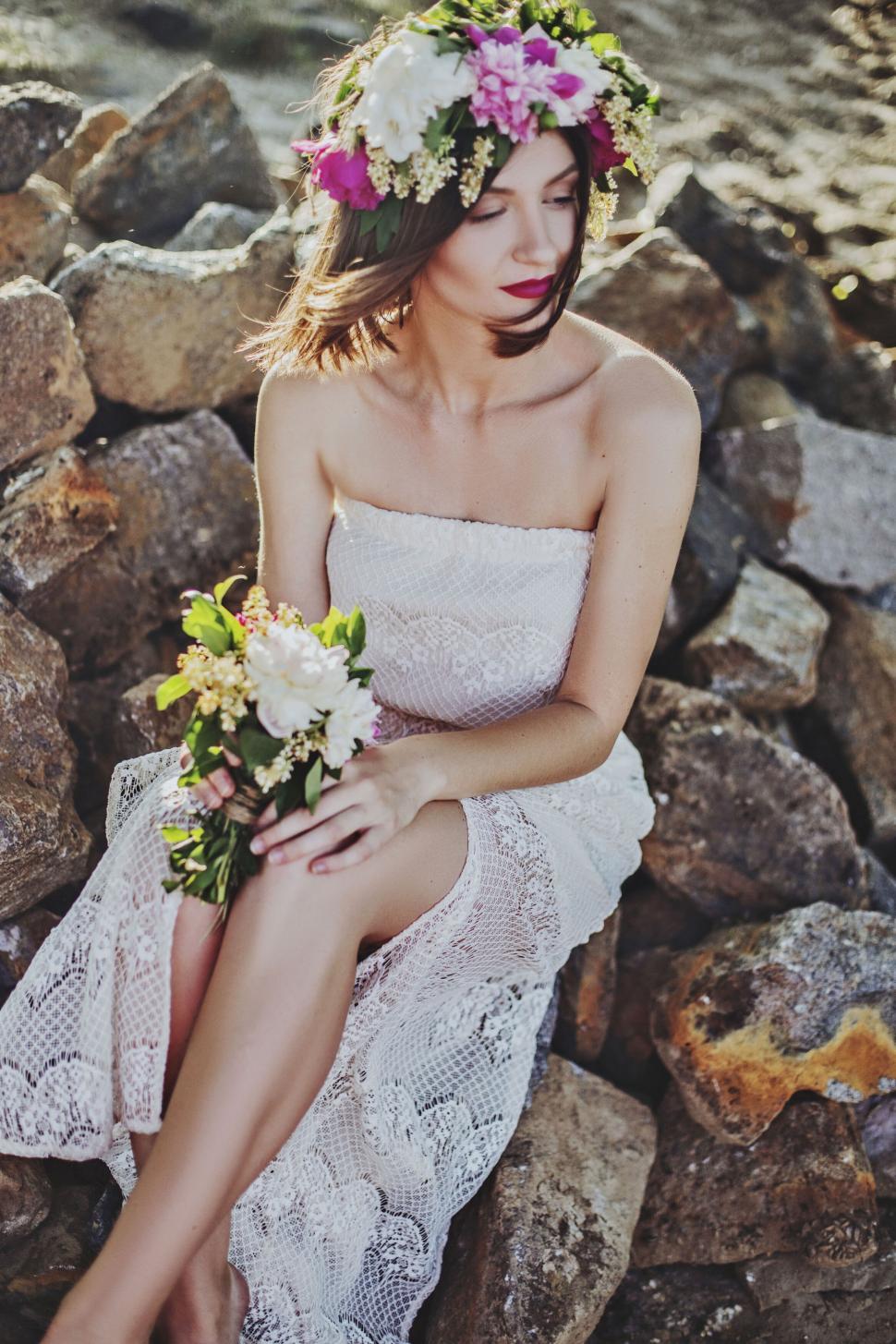 Free Image of Woman sitting on rocks with flower crown 