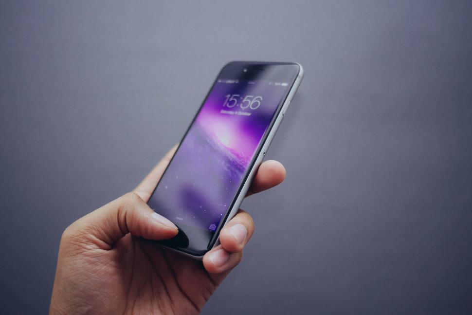 Free Image of Hand holding a smartphone with purple wallpaper 
