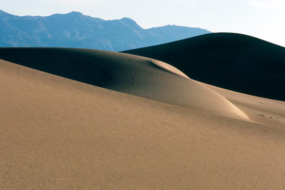 Free Image of Sand Dunes With Mountains in the Background 