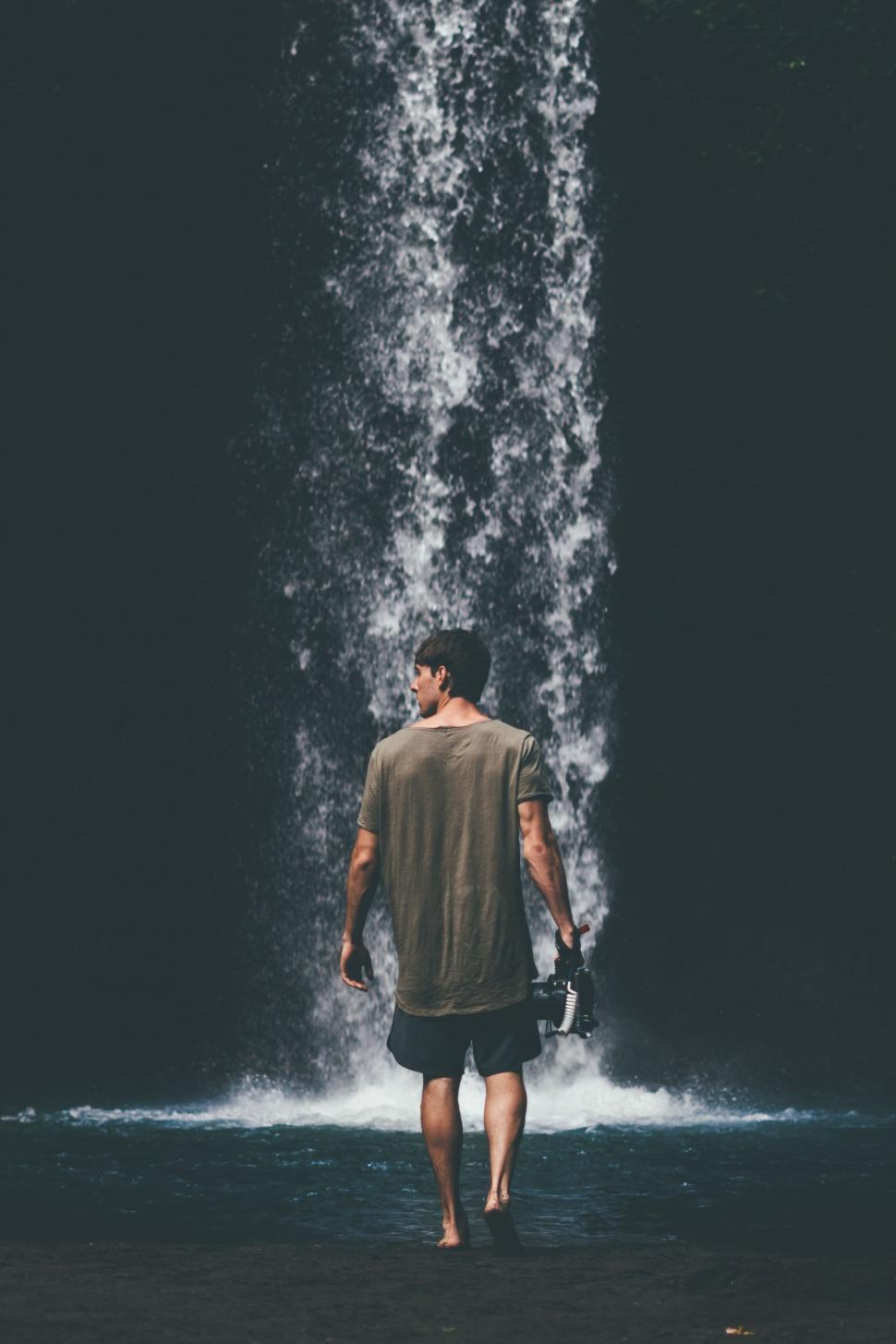Free Image of Man admiring waterfall in forest 
