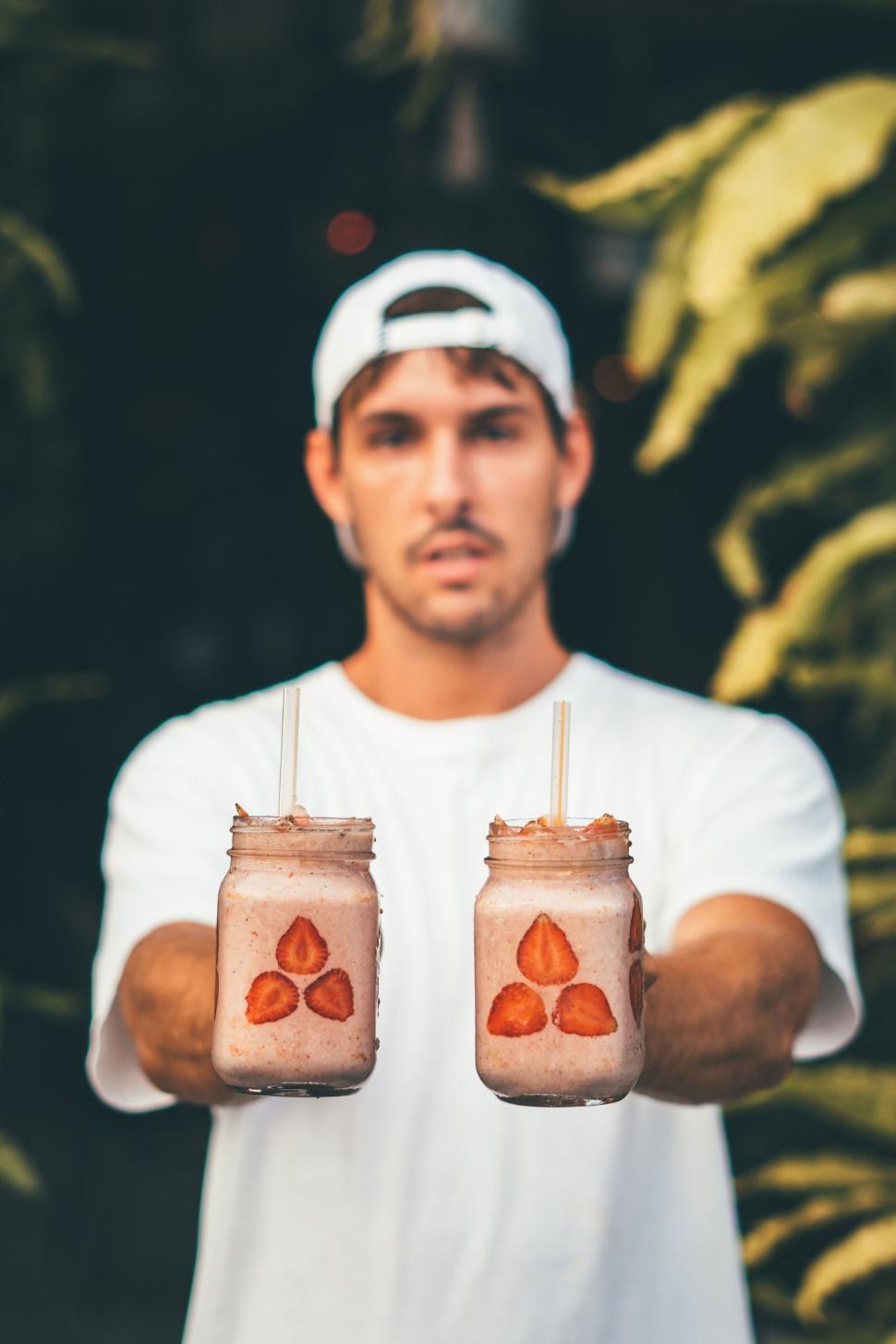 Free Image of Man holding smoothies with a focused look 