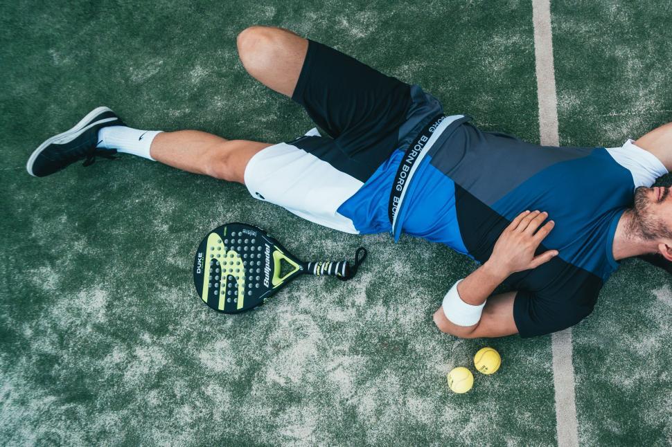 Free Image of Paddle tennis player resting on court 